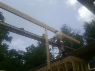 Carpenter setting a ridge beam over a new addition frame — Ice Dam Removal by Roofing Brothers in Bradenton Beach