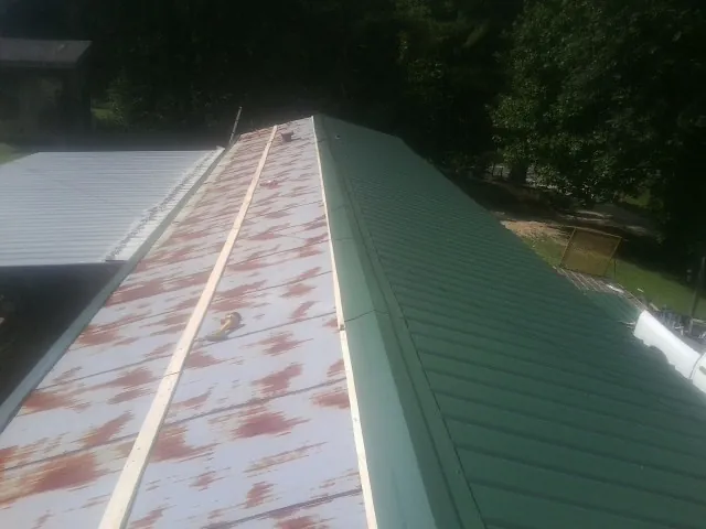 Old rusted panels beside newly installed green metal roofing — Wind Damage Roof Repair by Roofing Brothers in Bradenton Beach