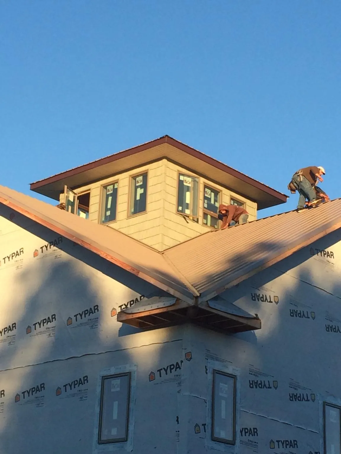 Roofers working around a rooftop cupola on a new metal roof at sunset — Roof Waterproofing in Bradenton Beach by Roofing Brothers
